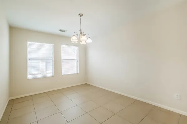 a view of an empty room with chandelier fan