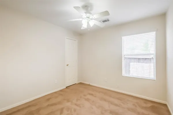 an empty room with a chandelier fan and windows