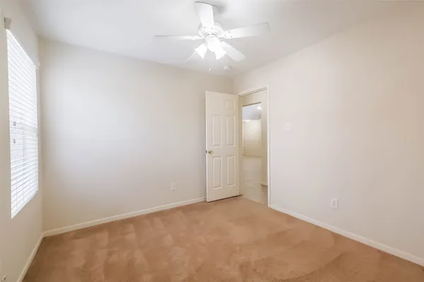 an empty room with windows and fan