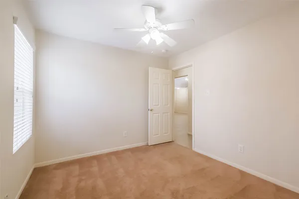 an empty room with a window and a fan