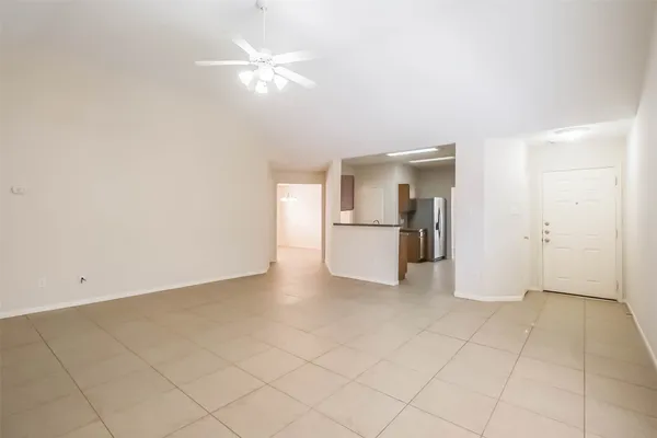 an empty room with a kitchen and a ceiling fan
