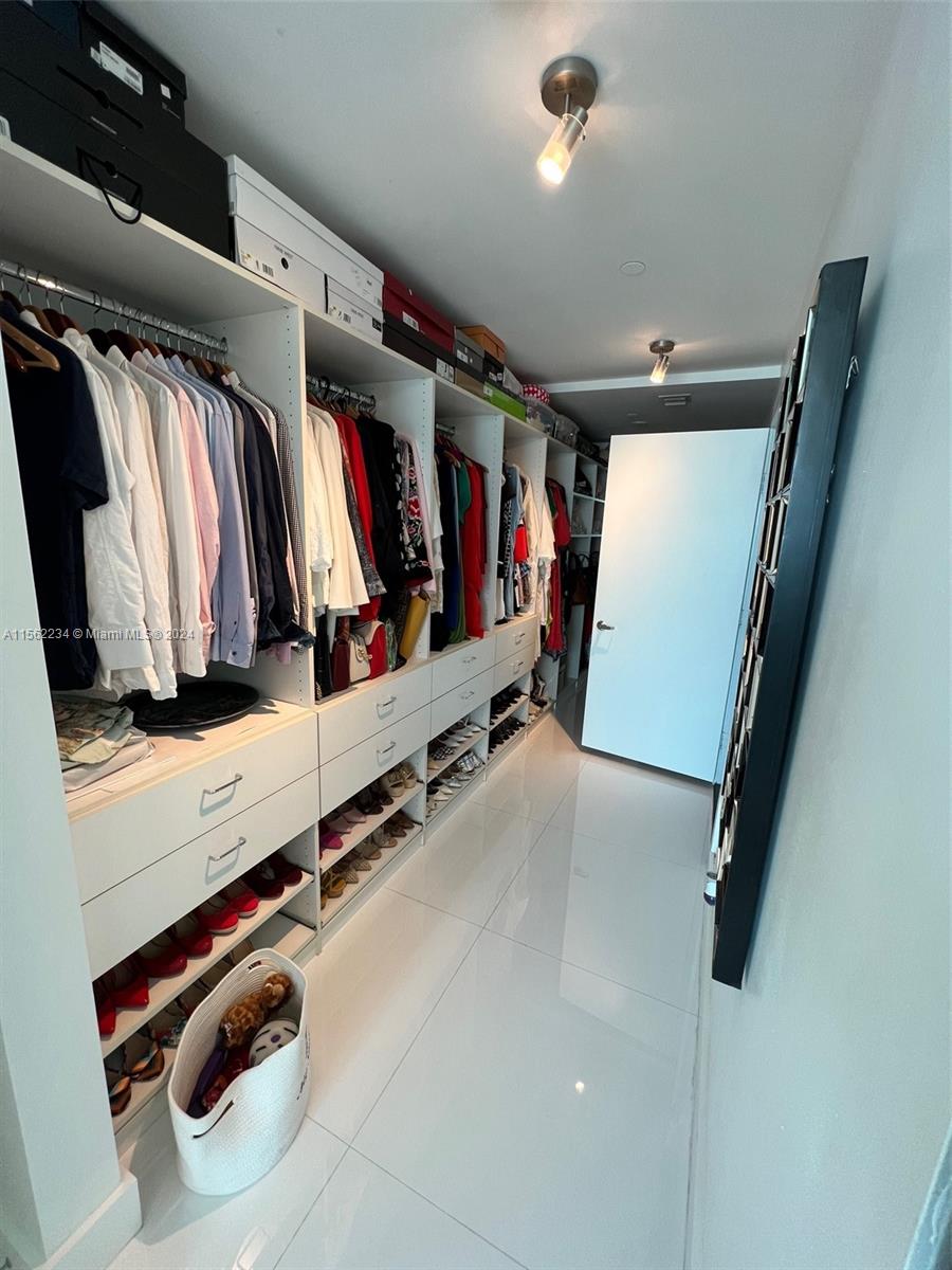 a view of walk in closet with clothes and shoes