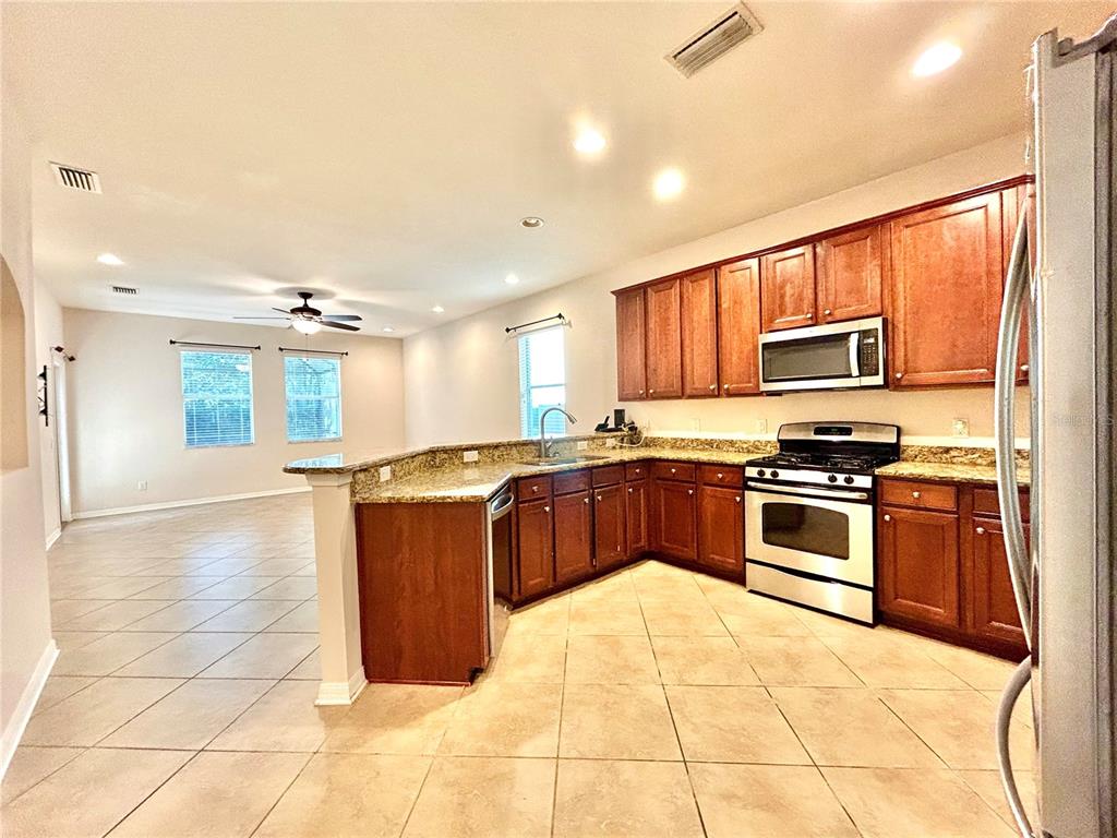 11210 Roseate Drive Tampa, FL 33626 - Photo 8 of 50 a large kitchen with kitchen island granite countertop a stove top oven a sink a counter space and cabinets