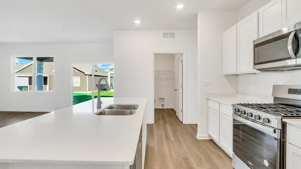 a kitchen with stainless steel appliances a white stove top oven a sink dishwasher and a microwave with wooden floor