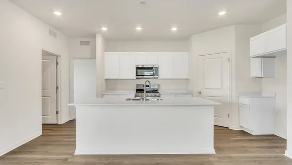 a large white kitchen with kitchen island a sink a center island stainless steel appliances and a counter top space