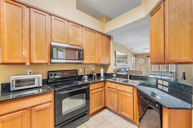 a kitchen with stainless steel appliances granite countertop a refrigerator a stove top oven and sink