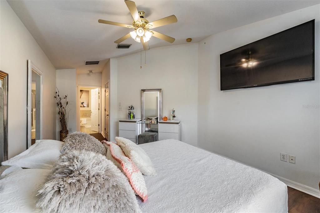 12204 Luftburrow Lane Hudson, FL 34669 - Photo 21 of 33 a bedroom with a large bed a flat tv screen and a chandelier