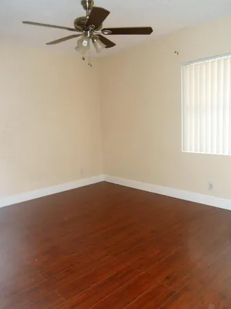 an empty room with wooden floor fan and windows