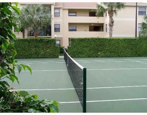a view of a tennis court with plants in front of house