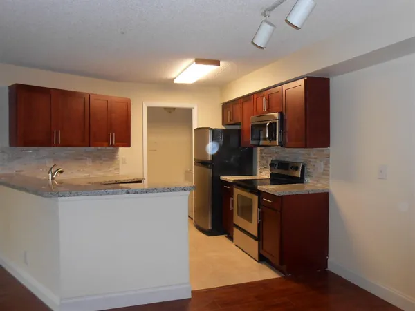 a kitchen with stainless steel appliances granite countertop a sink stove microwave and refrigerator