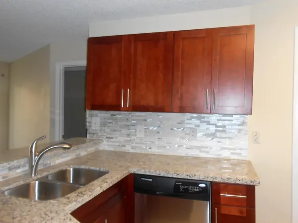 a kitchen with granite countertop a sink dishwasher stove and cabinets