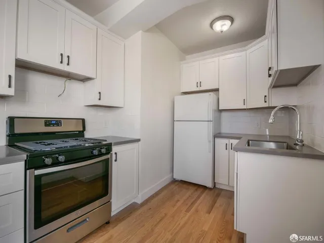 a kitchen with granite countertop wooden cabinets stainless steel appliances and a wooden floor