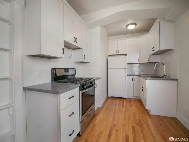 a kitchen with cabinets wooden floor and stainless steel appliances