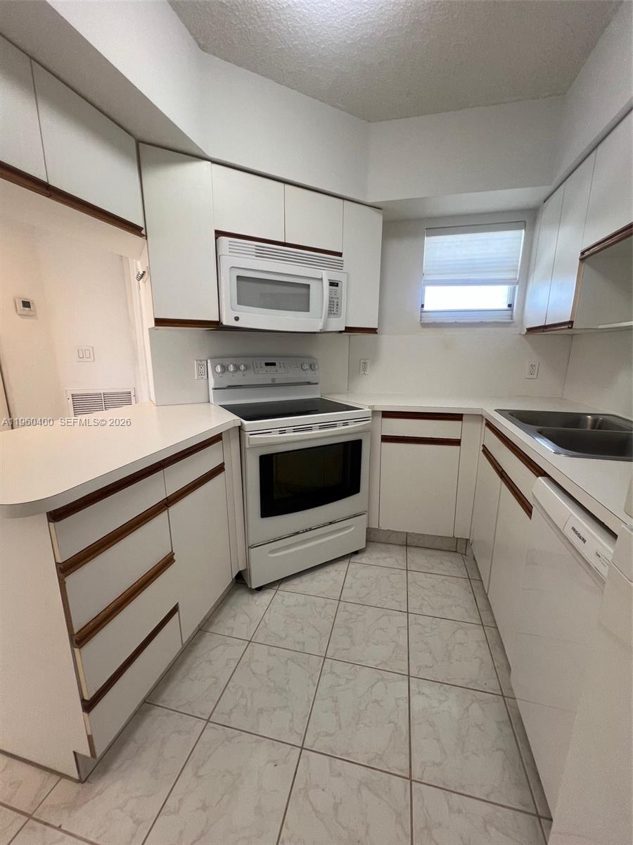 9156 Collins Avenue, Unit 502 Surfside, FL 33154 - Photo 3 of 20 a kitchen with stainless steel appliances a stove sink and cabinets