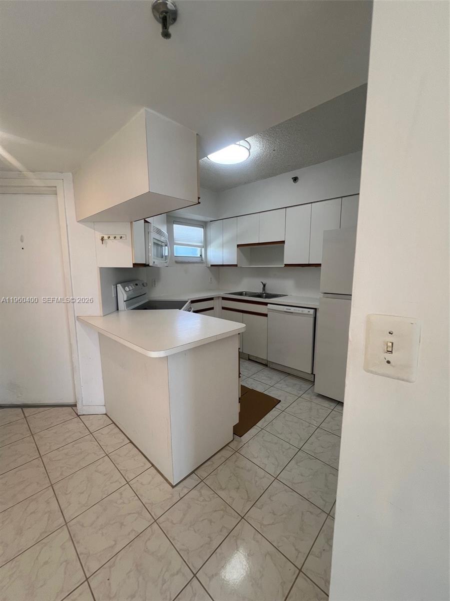 9156 Collins Avenue, Unit 502 Surfside, FL 33154 - Photo 4 of 20 a kitchen with a stove top oven and cabinets