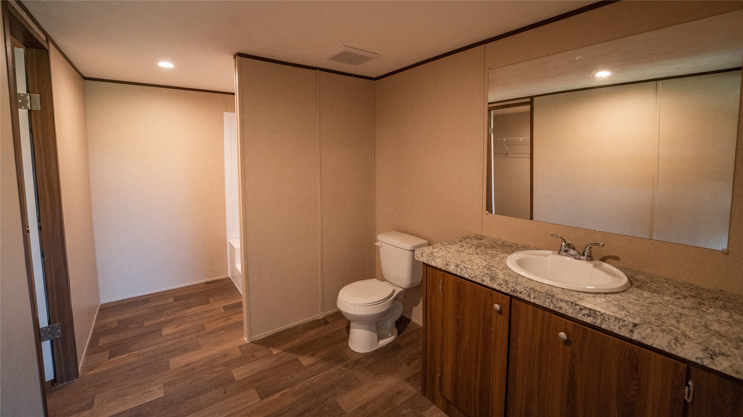 1121 Callihan Road Luling, TX 78648 - Photo 11 of 35 Full bathroom featuring wood finished floors, vanity, a bathtub, and recessed lighting