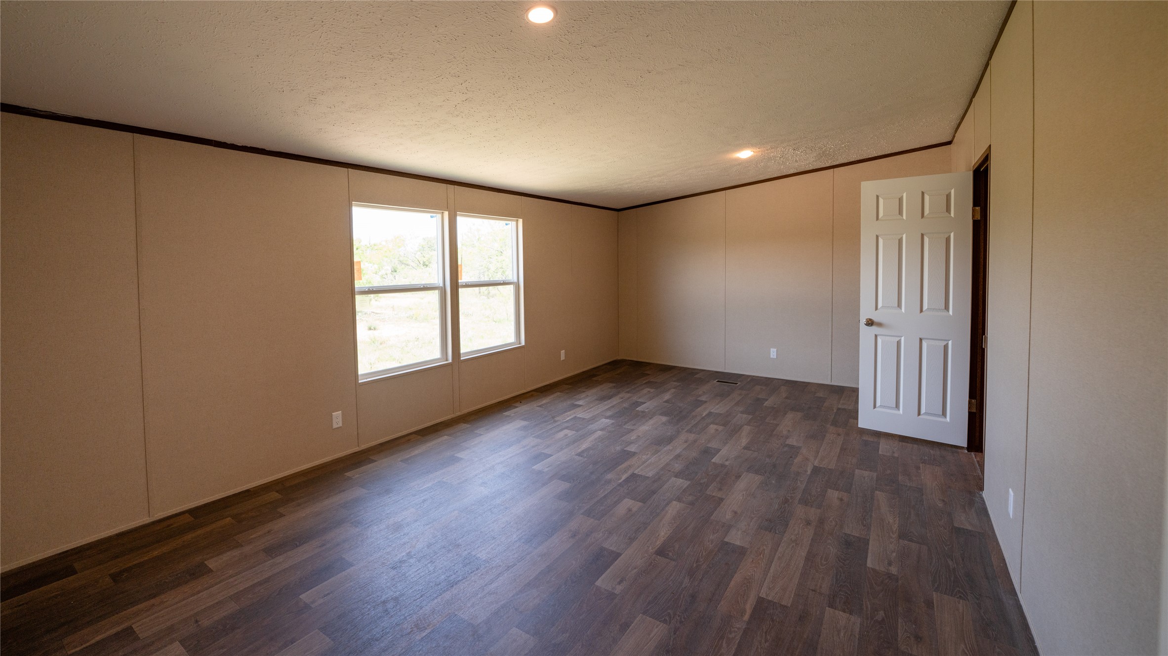 1121 Callihan Road Luling, TX 78648 - Photo 13 of 35 Unfurnished room featuring a textured ceiling, crown molding, a decorative wall, dark wood-type flooring, and recessed lighting
