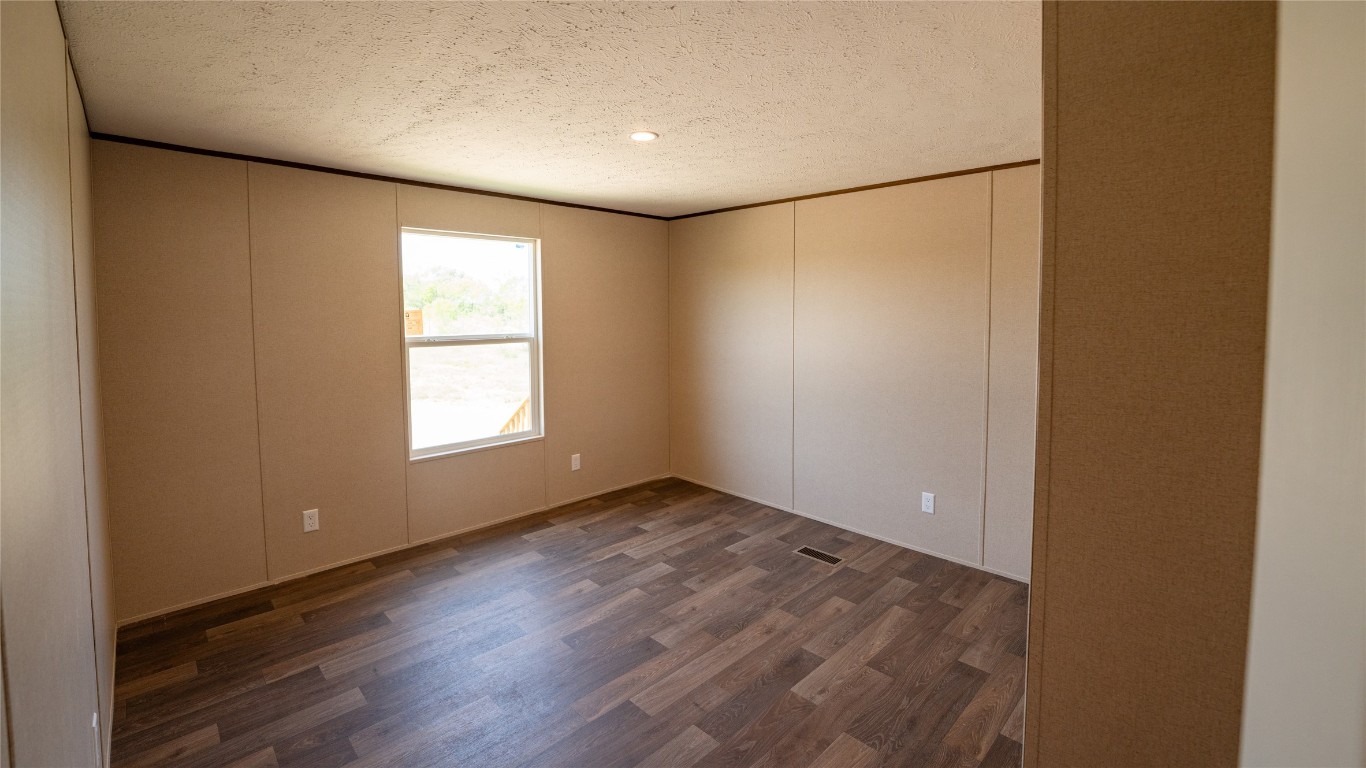 1121 Callihan Road Luling, TX 78648 - Photo 19 of 35 an empty room with wooden floor and windows with curtains