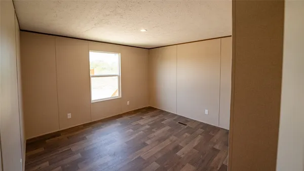 an empty room with wooden floor and windows with curtains