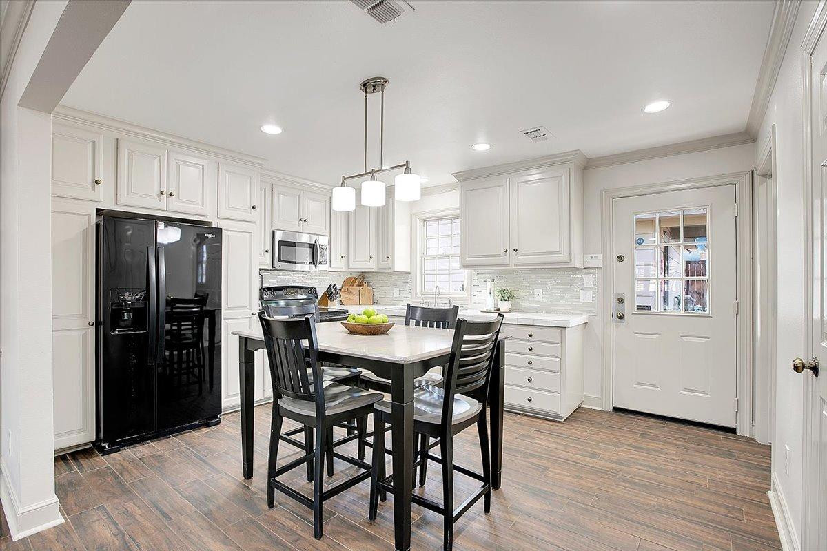 3203 32nd Street Lubbock, TX 79410 - Photo 9 of 27 a kitchen with a table chairs refrigerator and microwave