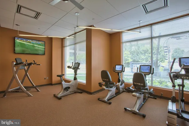a room with gym equipment pool table and windows