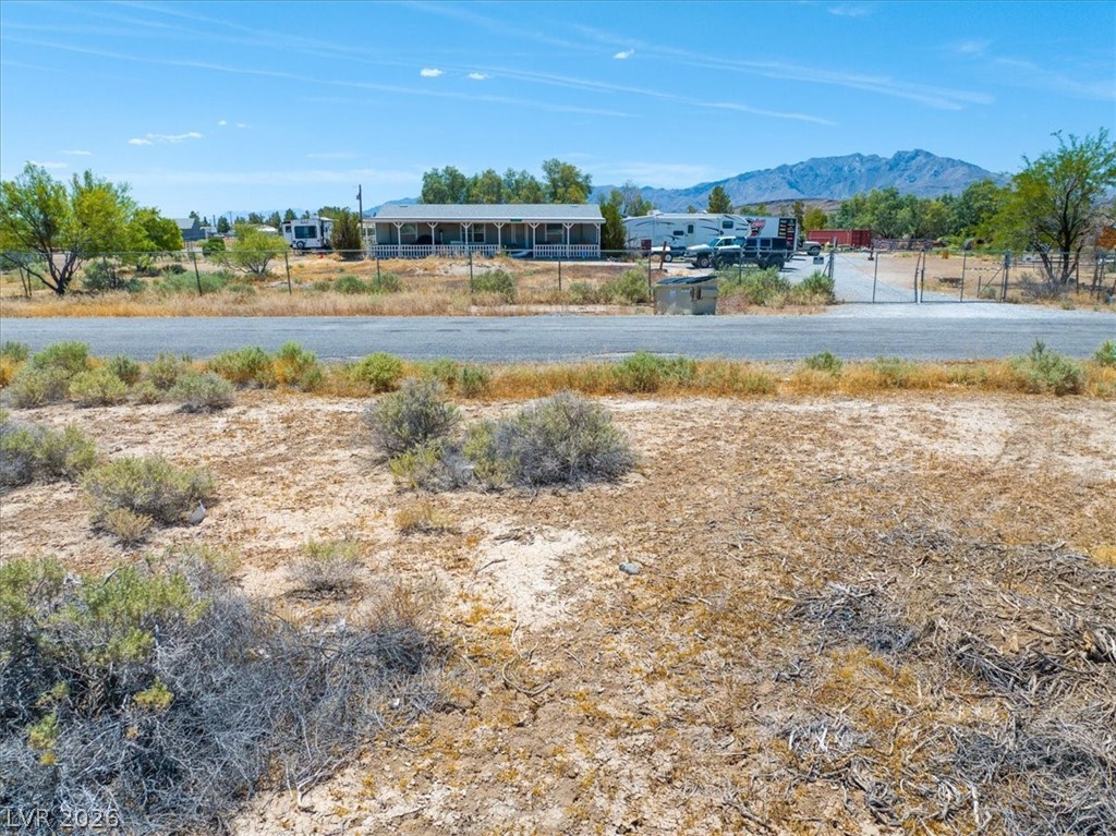 4580 Lawrence Road Pahrump, NV 89048 - Photo 11 of 40 A desert landscape unfolds with a modest home nestled against a backdrop of distant mountains.