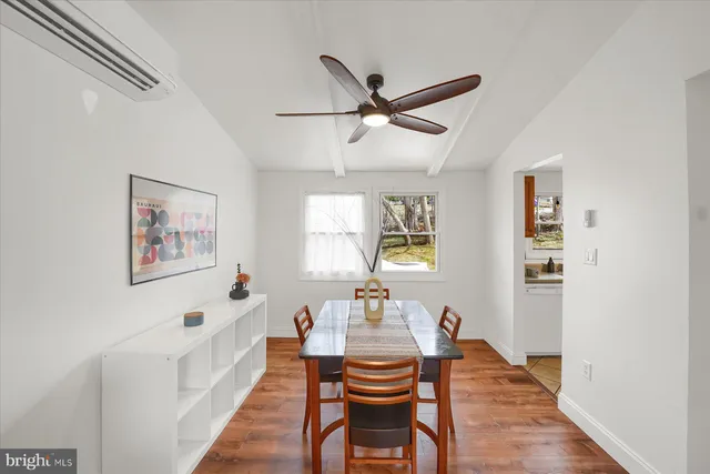a dining room with wooden floor and a ceiling fan