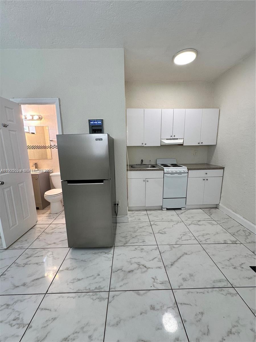 912 Northwest 9th Avenue, Unit 8 Hallandale Beach, FL 33009 - Photo 8 of 10 a kitchen with granite countertop a refrigerator a stove top oven and a sink