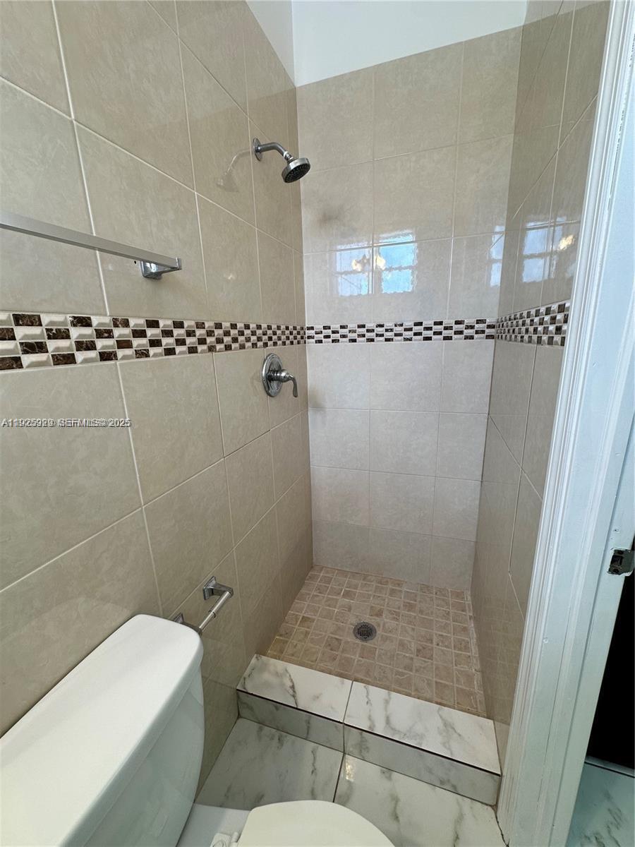912 Northwest 9th Avenue, Unit 8 Hallandale Beach, FL 33009 - Photo 10 of 10 a bathroom with a granite countertop shower a toilet and sink
