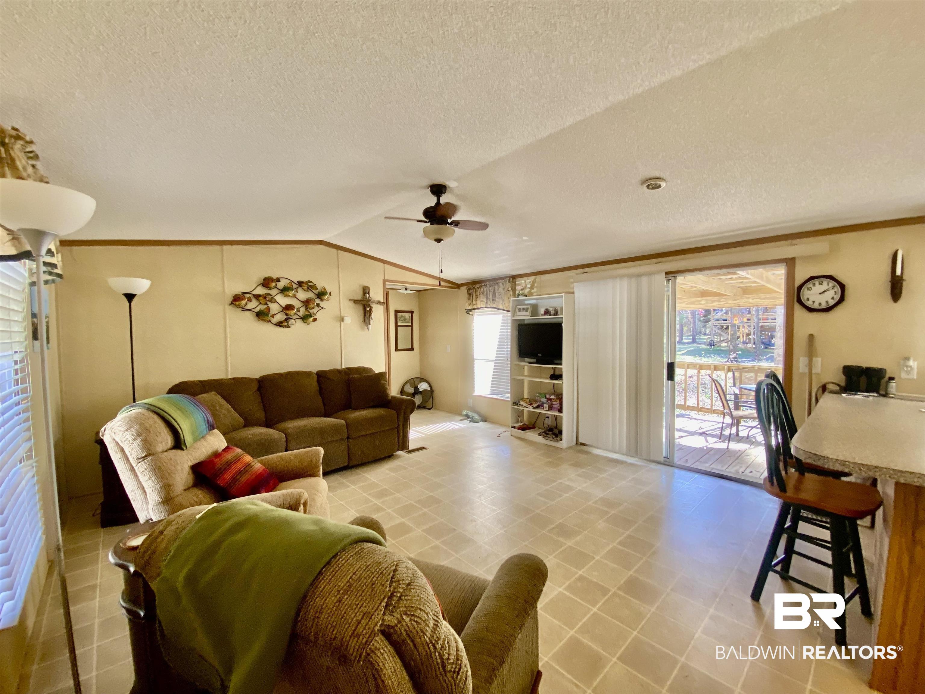 294 Eureka Way Uriah, AL 36480 - Photo 4 of 18 Living room with ornamental molding, lofted ceiling, plenty of natural light, and ceiling fan