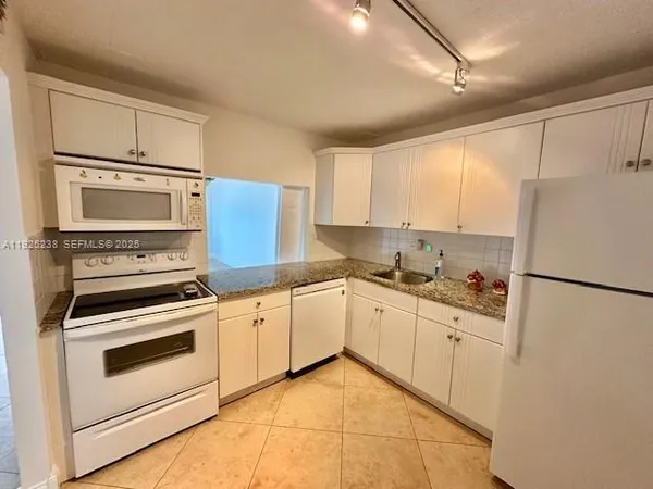 a kitchen with white cabinets and white appliances