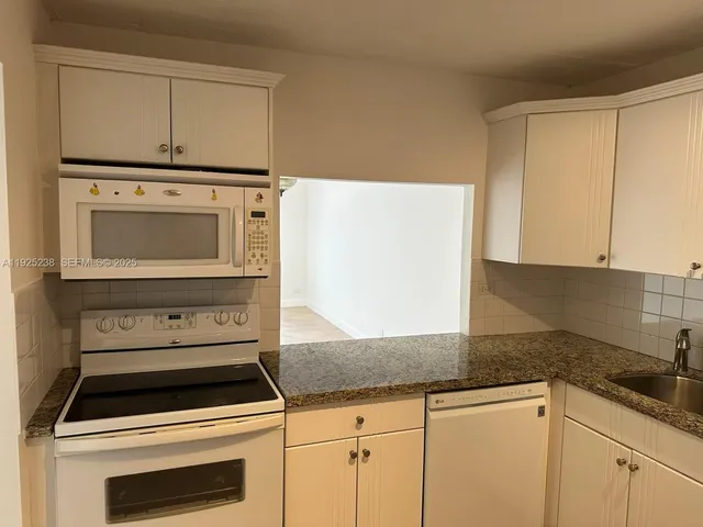 a kitchen with granite countertop white cabinets and white appliances