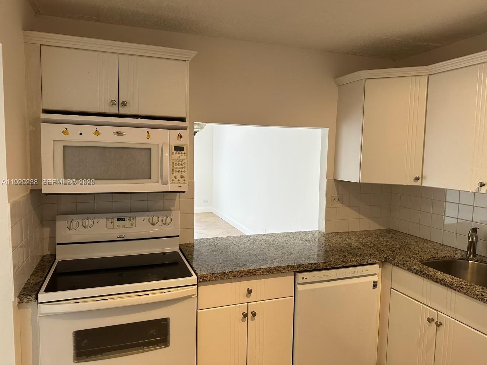 8101 Southwest 72nd Avenue, Unit 312W Miami, FL 33143 - Photo 3 of 19 a kitchen with granite countertop white cabinets and white appliances