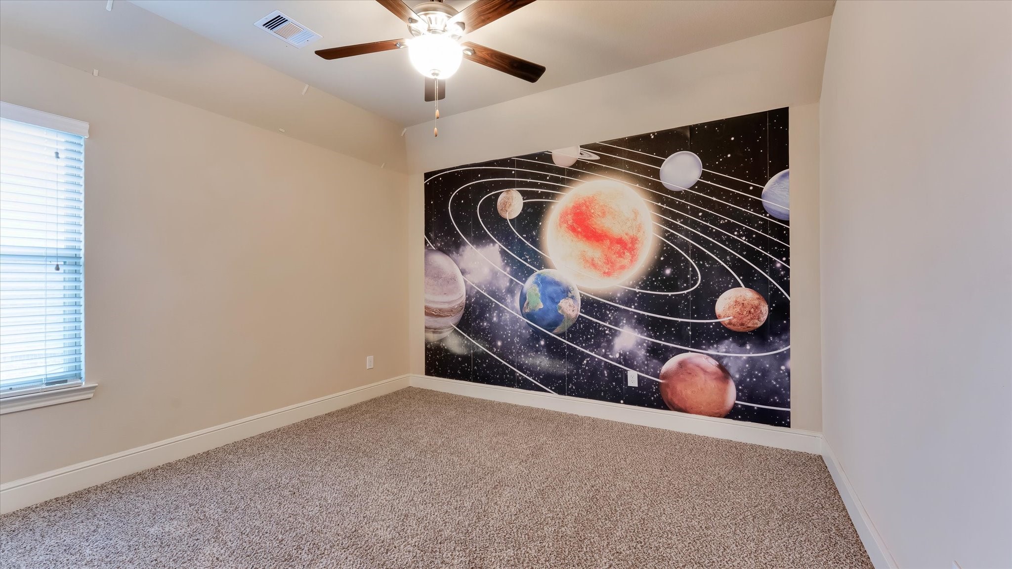 17211 Green Darter Conroe, TX 77385 - Photo 24 of 48 This bedroom features neutral walls and carpet, a ceiling fan, and a large window for natural light. A striking space-themed mural adds a playful touch.