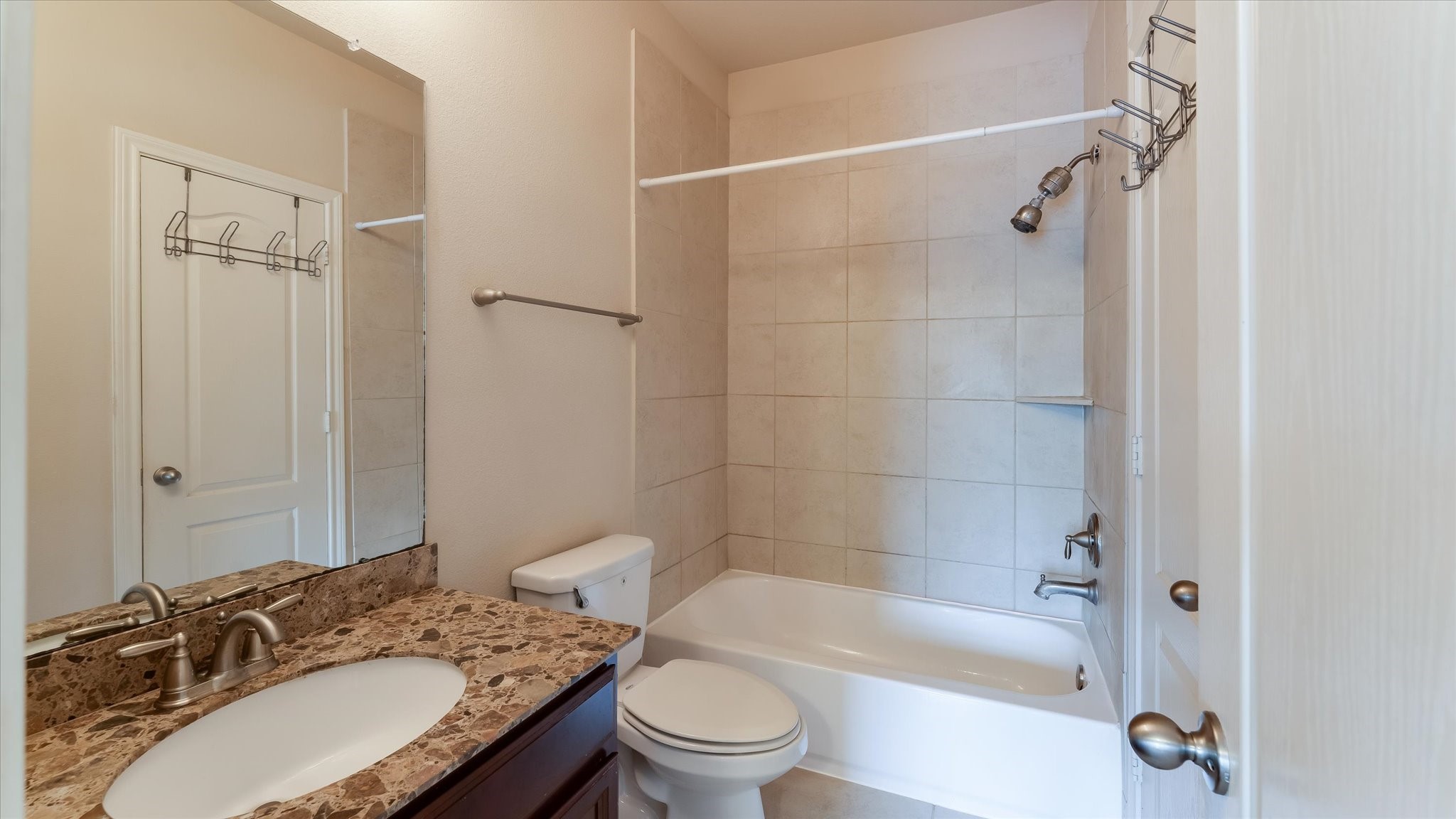 17211 Green Darter Conroe, TX 77385 - Photo 27 of 48 This bathroom features a clean, modern design with a tiled shower-tub combo, marble countertop vanity, and neutral color palette. Ideal for a contemporary home.
