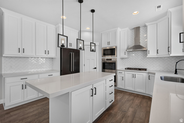 36 West Syracuse Road Vineyard, UT 84059 - Photo 15 of 56 White shaker cabinetry with dark hardware, quartz countertops, a herringbone tile backsplash, wood-finish flooring, and stainless steel appliances