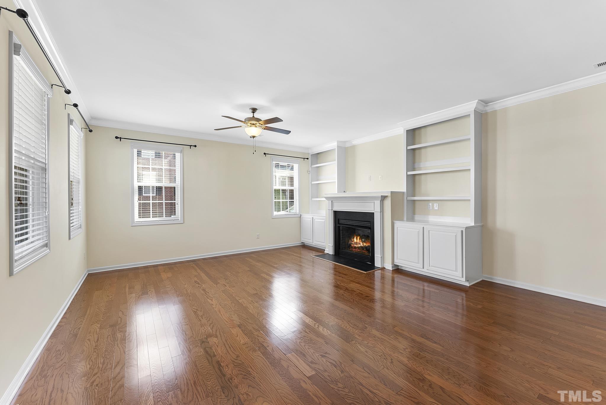 517 Dragby Lane Raleigh, NC 27603 - Photo 4 of 31 an empty room with wooden floor fireplace and windows
