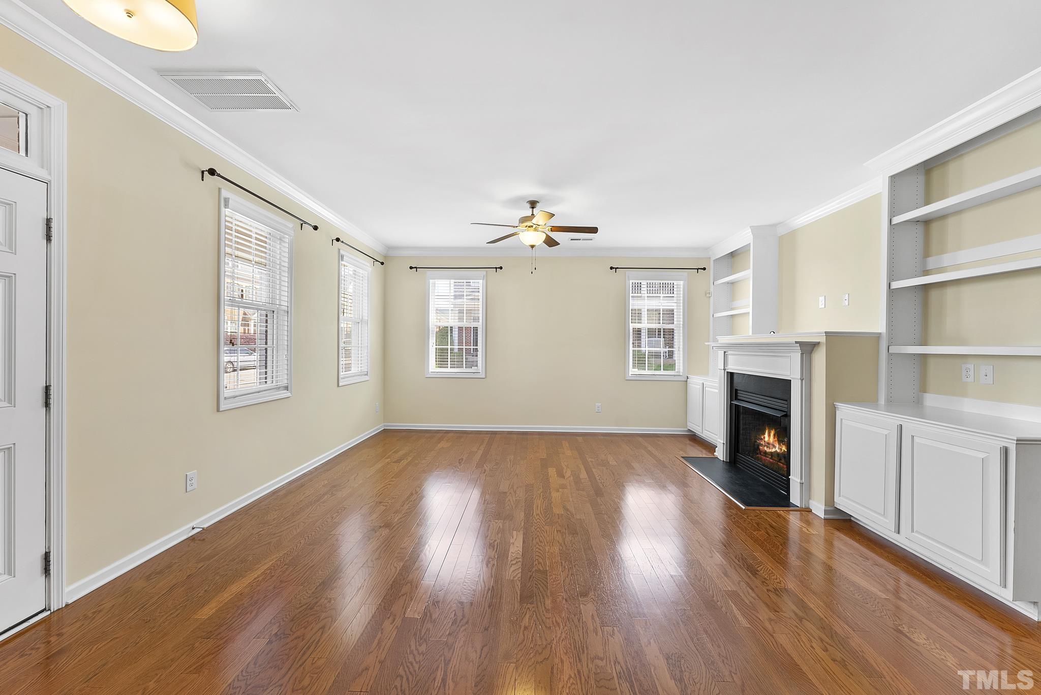 517 Dragby Lane Raleigh, NC 27603 - Photo 5 of 31 an empty room with windows a fireplace and wooden floor
