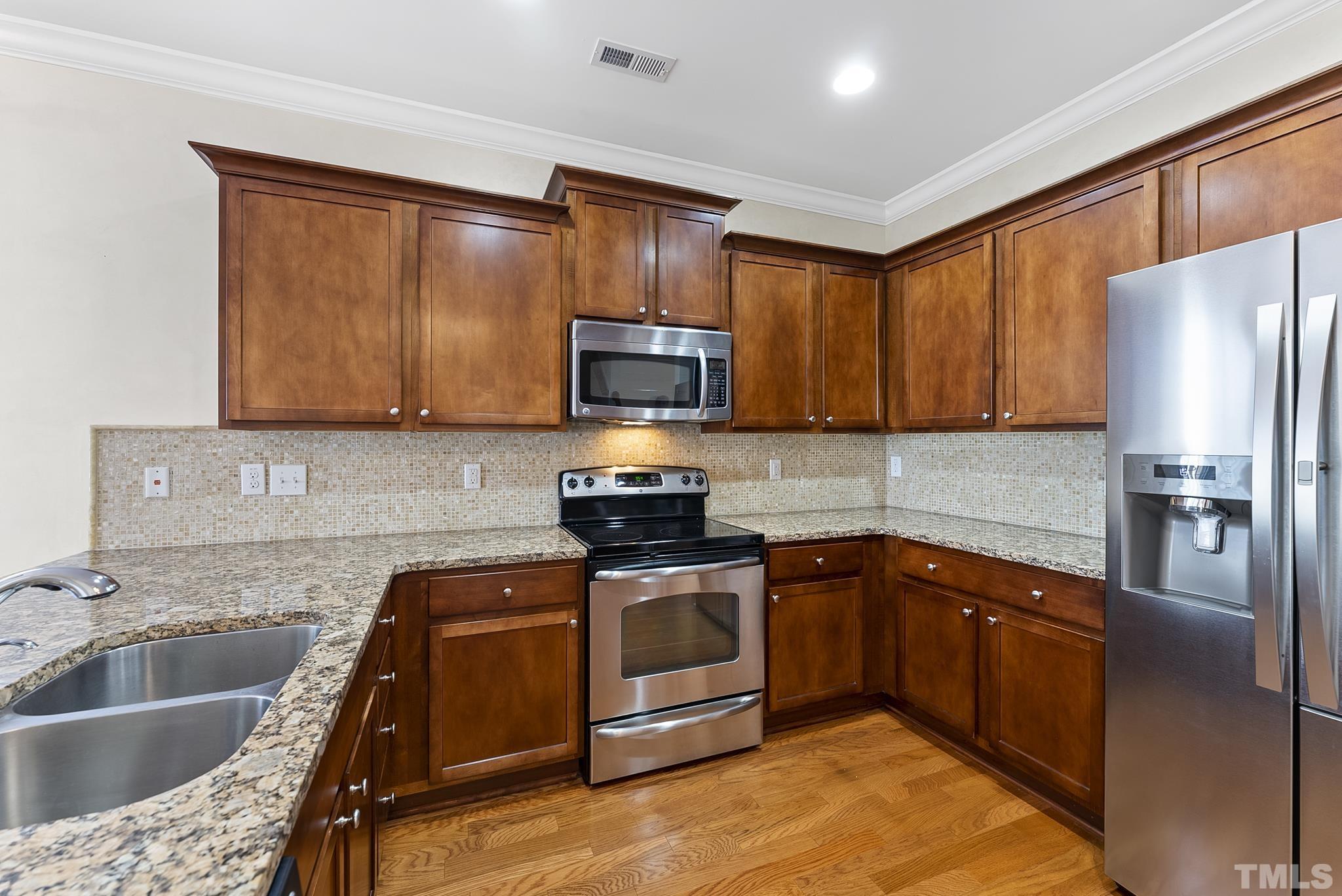 517 Dragby Lane Raleigh, NC 27603 - Photo 9 of 31 a kitchen with stainless steel appliances granite countertop a sink stove and refrigerator