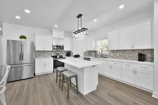 a kitchen that has a lot of white cabinets and stainless steel appliances
