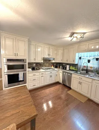 a large kitchen with cabinets a sink a window and stainless steel appliances