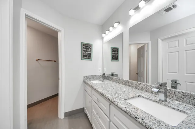 a bathroom with a granite countertop double vanity sink and a mirror