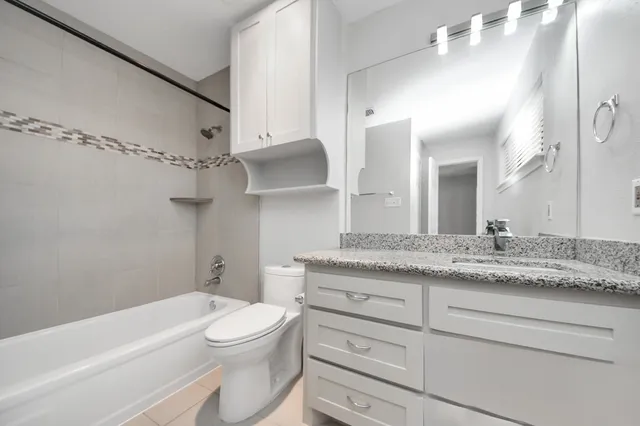 a bathroom with a granite countertop sink a toilet and bathtub
