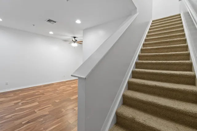 an empty room with windows and ceiling fan