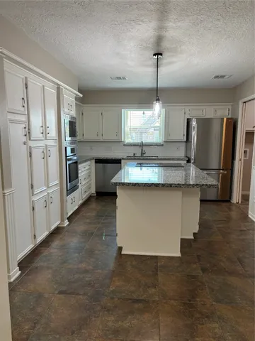 a kitchen with kitchen island granite countertop a sink stove and refrigerator