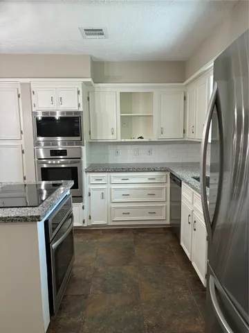 a kitchen with stainless steel appliances granite countertop a stove top oven a sink and a refrigerator
