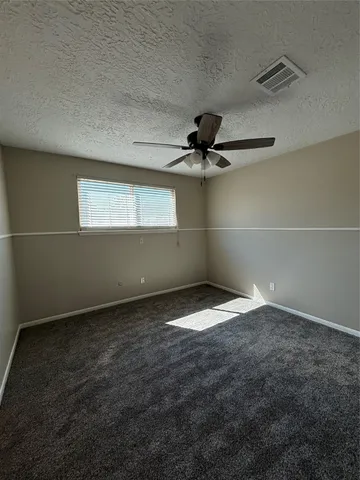 an empty room with a window and a ceiling fan
