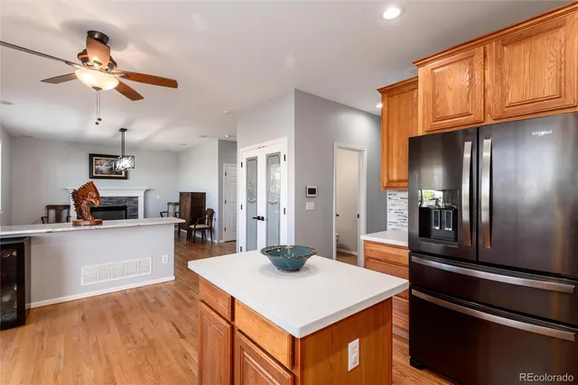 a kitchen with stainless steel appliances kitchen island granite countertop a refrigerator a stove and a sink with wooden floor