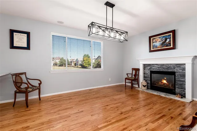 a view of a livingroom with a fireplace a chandelier and wooden floor