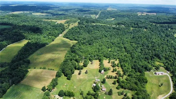 an aerial view of a houses with a lush green hillside